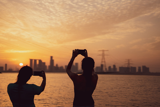 Silhouettes of two ladies and Abu Dhabi skyline as a background with sunset