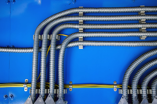 Cableado, distribución de cables en un corrugado metálico sobre un fondo azul photo