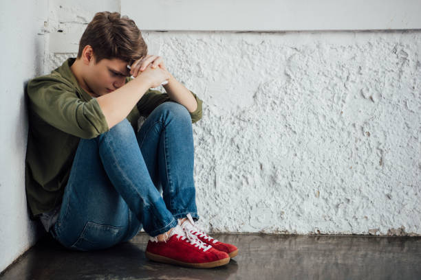 istock sad teenager in jeans holding smartphone and sitting on floor 1188912708