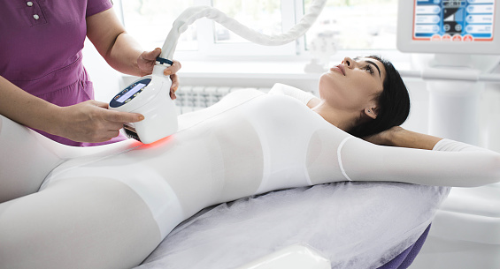 making slim body with the anti-cellulite LPG massage. woman dressed in a special suit getting a cellulite removal massage on belly