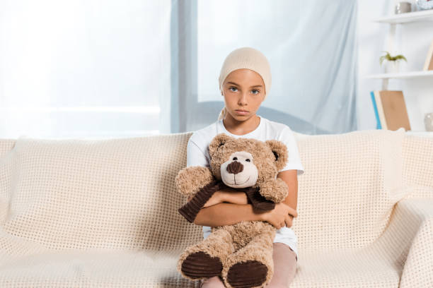 istock sick child sitting on sofa and holding teddy bear 1188912827
