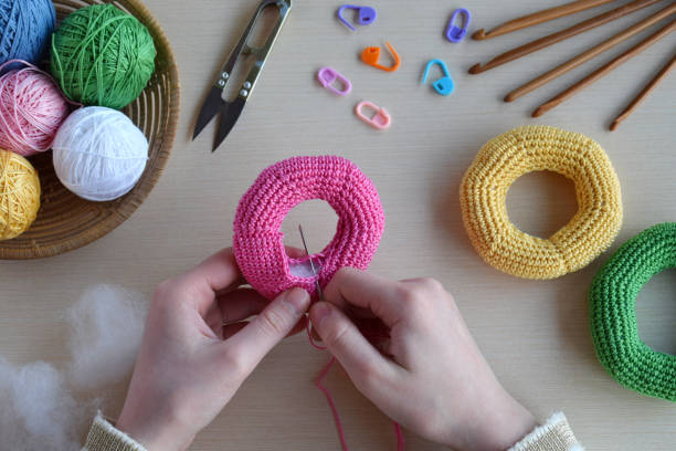 istock Making crochet pyramid from colored rings. Toy for babies and toddlers to learn mechanical skills and colors. On the table threads, needles, hook, cotton yarn. Handmade crafts. DIY concept. 1188913019