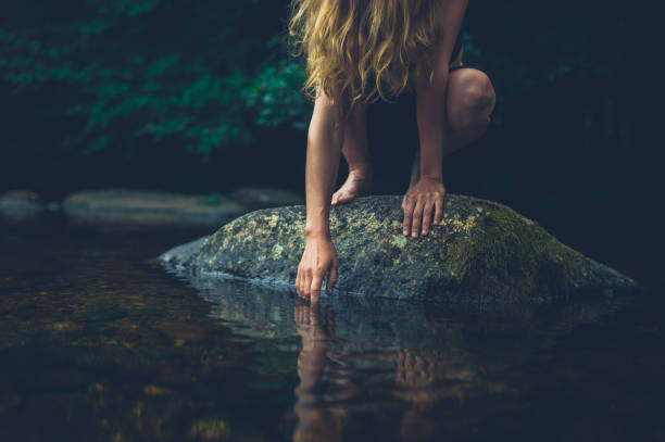 Young woman sitting on rock in a river stock photo