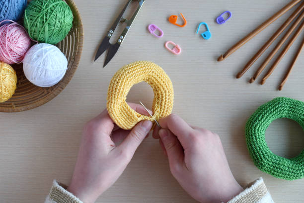 istock Making crochet pyramid from colored rings. Toy for babies and toddlers to learn mechanical skills and colors. On the table threads, needles, hook, cotton yarn. Handmade crafts. DIY concept. 1188914668