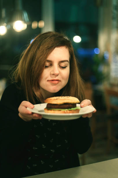 istock Young woman eating a hamburger 1188917526
