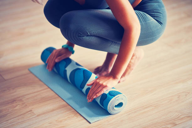 istock Young woman rolling yoga mat at home 1188918918