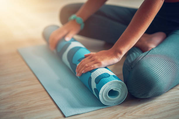 istock Young woman rolling yoga mat at home 1188920959