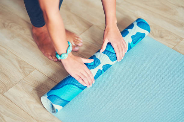 istock Young woman rolling yoga mat at home 1188921095