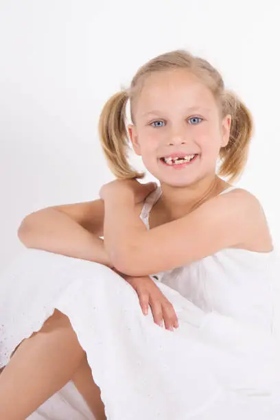 7 year old blond girl smiling to the camera with lack of milk teeth