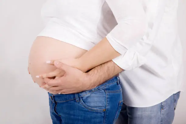 Couple holding pregnant belly with white background made in studio