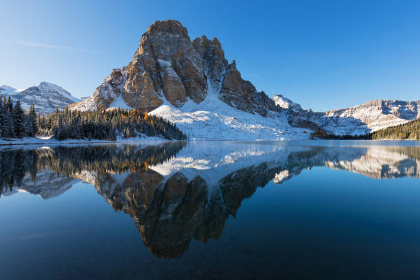 Winter morning. Mount Assiniboine, also known as Assiniboine Mountain, is a pyramidal peak mountain located on the Great Divide, on the British Columbia/Alberta border in Canada. Canada first snow lake magog photos stock pictures, royalty-free photos & images