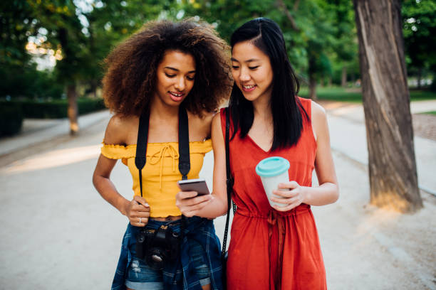 istock Beautiful girls walking together and using mobile app 1188923833