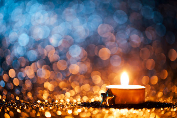 lighted candle on defocused blue background - christmas tea light - advento imagens e fotografias de stock