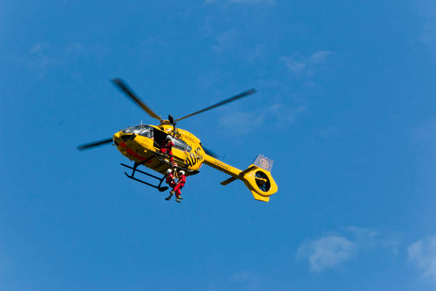 un ambulancier paramédical et une personne blessée se font soulever par un hélicoptère - rescue mountain horizontal three people photos et images de collection