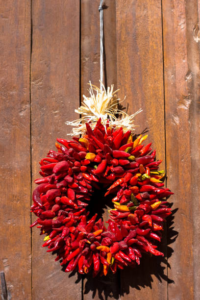 santa fe stil: weihnachten rot ristra kranz, alte holztür - wreath chili pepper pepper ristra stock-fotos und bilder