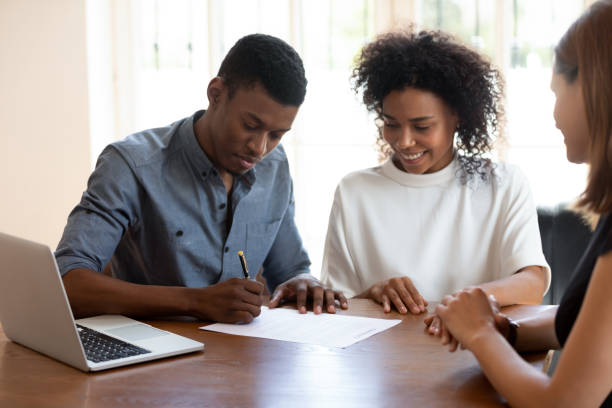 istock Happy young banking worker watching african ethnicity client signing agreement. 1188929895