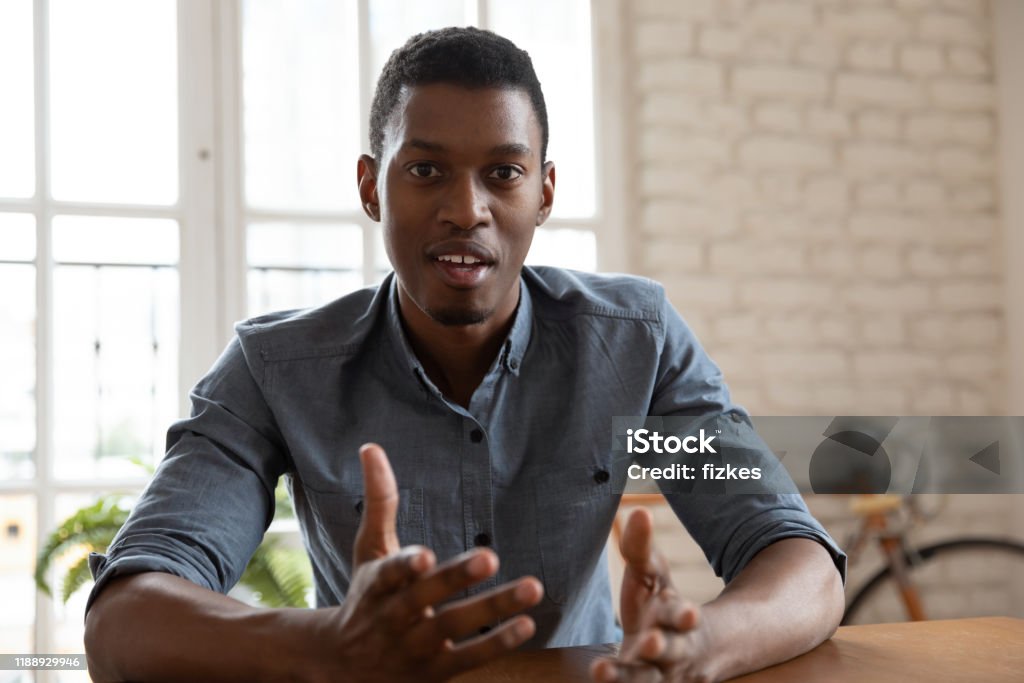 Focused young african american male speaker recording educational lecture. Head shot close up webcam view focused young african american male speaker coach trainer recording educational lecture. Focused mixed race businessman discussing project via video call with clients. Discussion Stock Photo