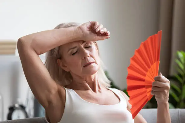 Photo of Tired overheated middle aged lady wave fan complain on heat