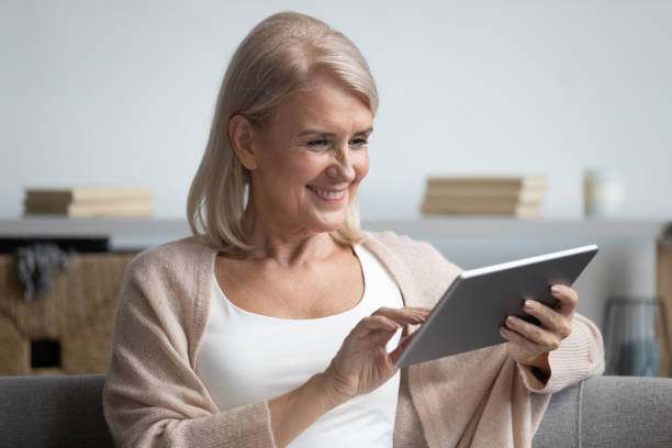 istock Happy middle aged woman using tablet computer at home 1188934120