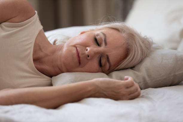 istock Calm serene older woman sleeping alone in bed, closeup view 1188934137