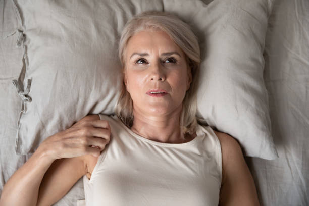 donna di mezza età insonnia che giace sveglia a letto, vista dall'alto - solitude loneliness bedroom empty foto e immagini stock