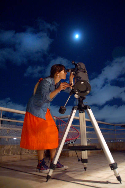 istock Woman looking at the moon through a telescope 1188935220
