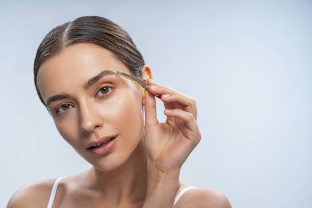 istock Attractive brunette female correcting her thick eyebrows 1188937212
