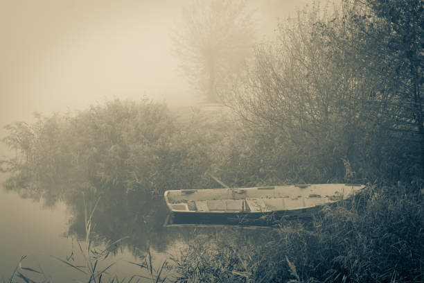 Old row boat at the waterfront in a misty frozen scenery early in the morning, picture taken at lake Kotermeerstal the Netherlands, province Overijssel