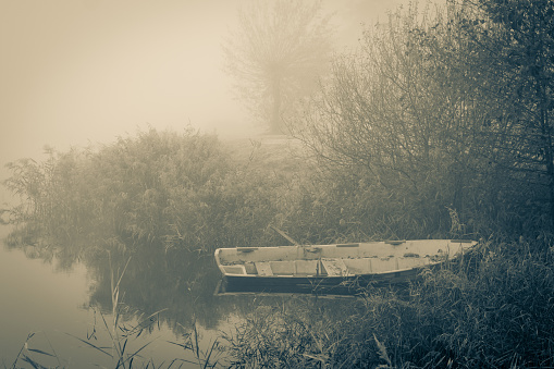 Old row boat at the waterfront in a misty frozen scenery early in the morning, picture taken at lake Kotermeerstal the Netherlands, province Overijssel