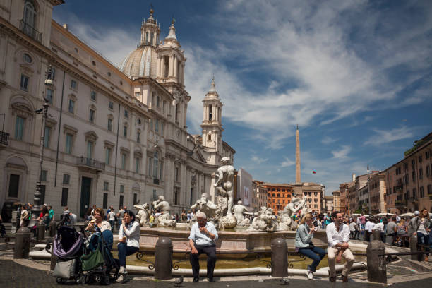 Navona Square in Rome Panoramic view of some people sitting on the Fontana del Moro with the church of Sant'Agnesse in Agone in the background, Piazza Navona, Rome fontana del moro stock pictures, royalty-free photos & images