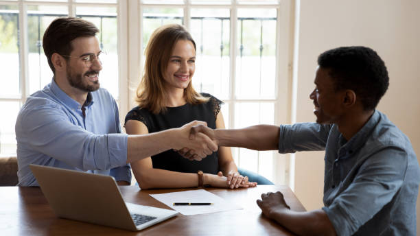 istock Young smiling clients shaking hands with african american financial advisor. 1188939614