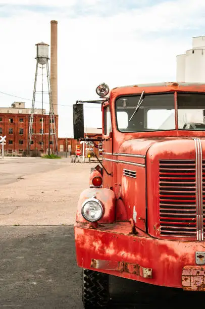 A vintage firetruck sits parked near the abandoned factory it protected when in use.