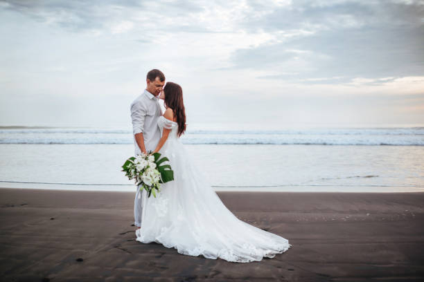 istock Elegant gorgeous bride and groom walking on ocean beach during sunset time. 1188942305