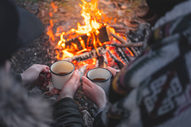 istock Two people warming hands with hot drinks by the bonfire. 1188946563