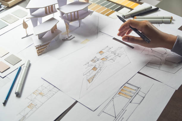 istock architect design working drawing sketch plans blueprints and making architectural construction model in architect studio 1188955544
