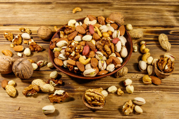 istock Mixed nuts on wooden table. Walnuts, pistachio, almond, peanut, cashew, hazelnut in ceramic bowl. Healthy eating concept 1188958732