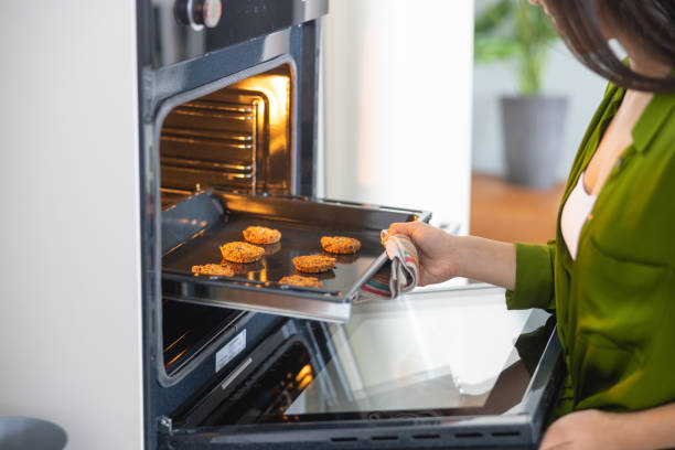 giovane casalinga asiatica che apre il forno a convezione - convection foto e immagini stock