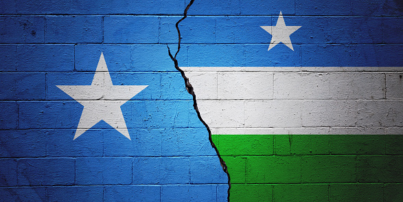 Cracked brick wall painted with a Somalian flag on the left and a Puntland flag on the right.