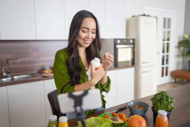 lächelnde junge dame, die ihre vitamine anschaut - nahrungsergänzungsmittel stock-fotos und bilder