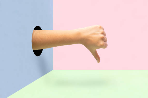 istock Hand making thumbs down like a disapproval sign on colorful background. 1188963924