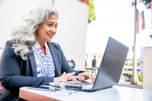 latina businesswoman usando laptop en cafe - leadership business women senior adult fotografías e imágenes de stock