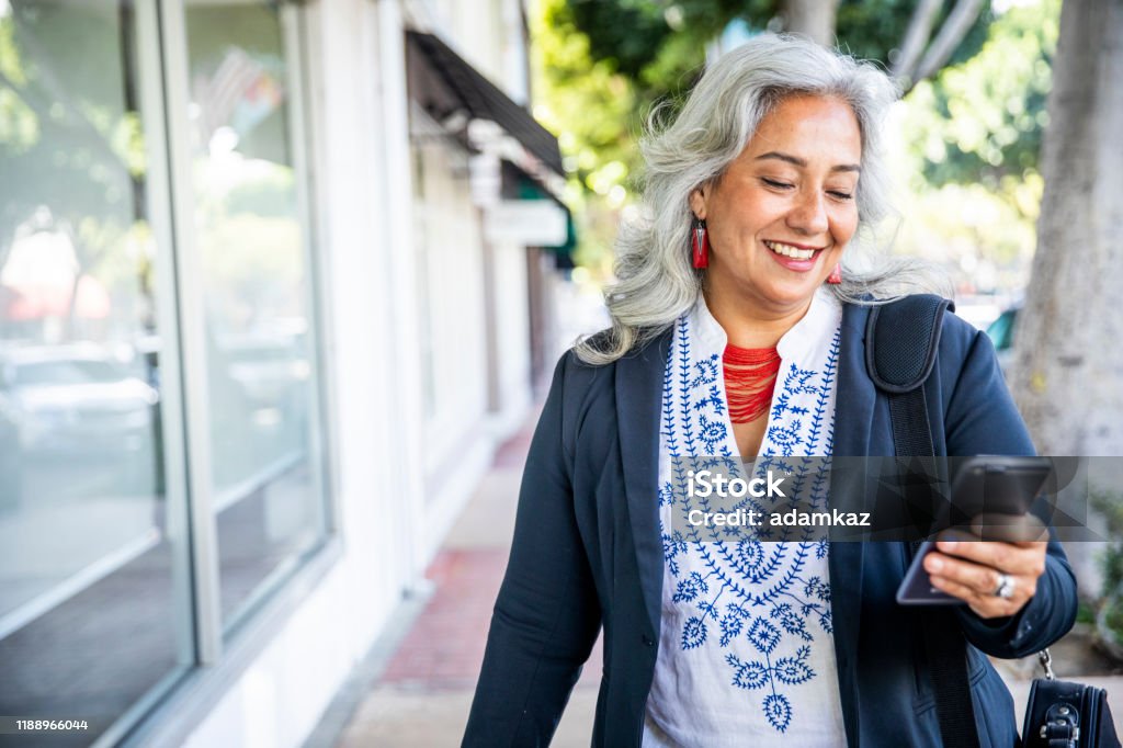Mexican Businesswoman Texting A mature Mexican businesswoman texting Senior Adult Stock Photo