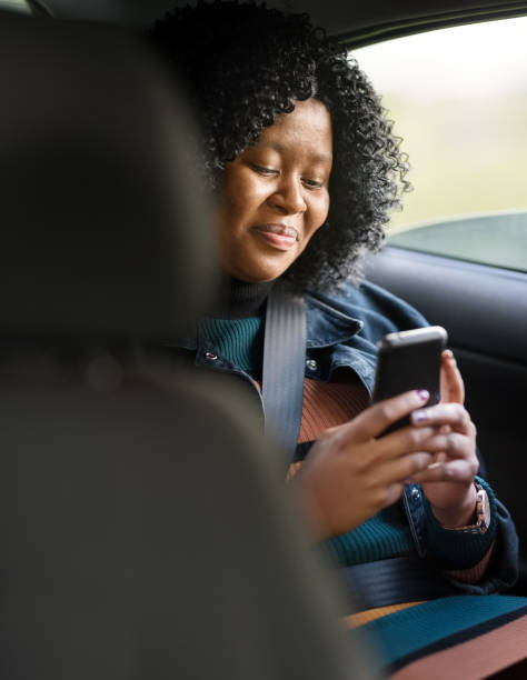 I am on my way Shot of a happy mature woman in back seat of car using her mobile phone travel destinations 20s adult adventure stock pictures, royalty-free photos & images