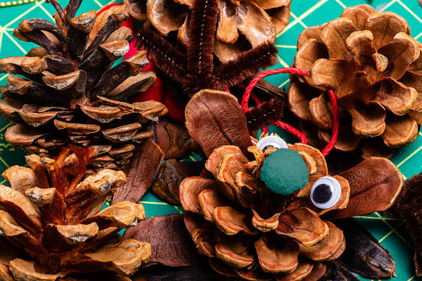istock A Macro image of various pine cone reindeer being created.  The pine cones are on a green cutting mat and have googly eyes. 1188970941