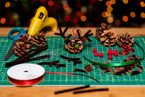 Family Holiday Crafting.  Making Christmas ornaments from pine cones.  A reindeer pinecone ornament!  Soft Focused Bokeh background has room for Copy.