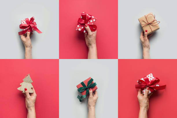 Female hands holding different gifts on grey and red. Xmas greeting card. Boxing day. Female hands holding different gifts and Christmas tree on grey. Xmas greeting card. Happy Boxing day. hand holding gift stock pictures, royalty-free photos & images