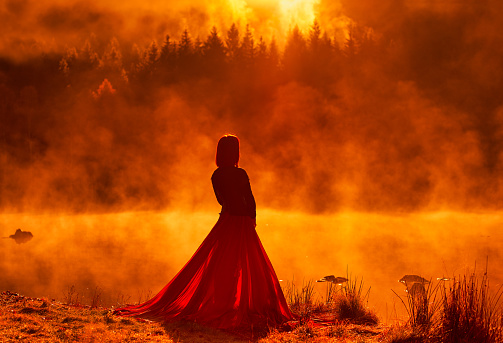 Rear view of woman wearing red skirt, posing in fairytale concept at the lake, autumn concept