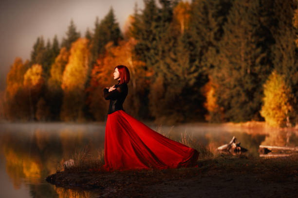 Woman wearing red skirt posing in fairytale concept at the lake, autumn concept