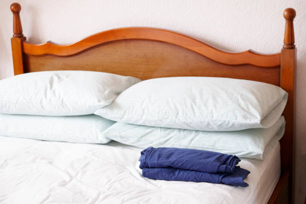 Bed linen laundry sheets pillows and folded pyjamas on wooden bed uk