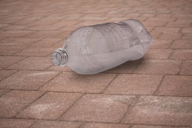 istock Empty plastic bottle lying on wooden boardwalk tossed away. Close up image with selective focus. Environment concept. Close up image. 1188985438